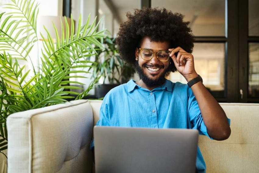 Banner image of man sitting on sofa with laptop Banner image of man sitting on sofa with laptop